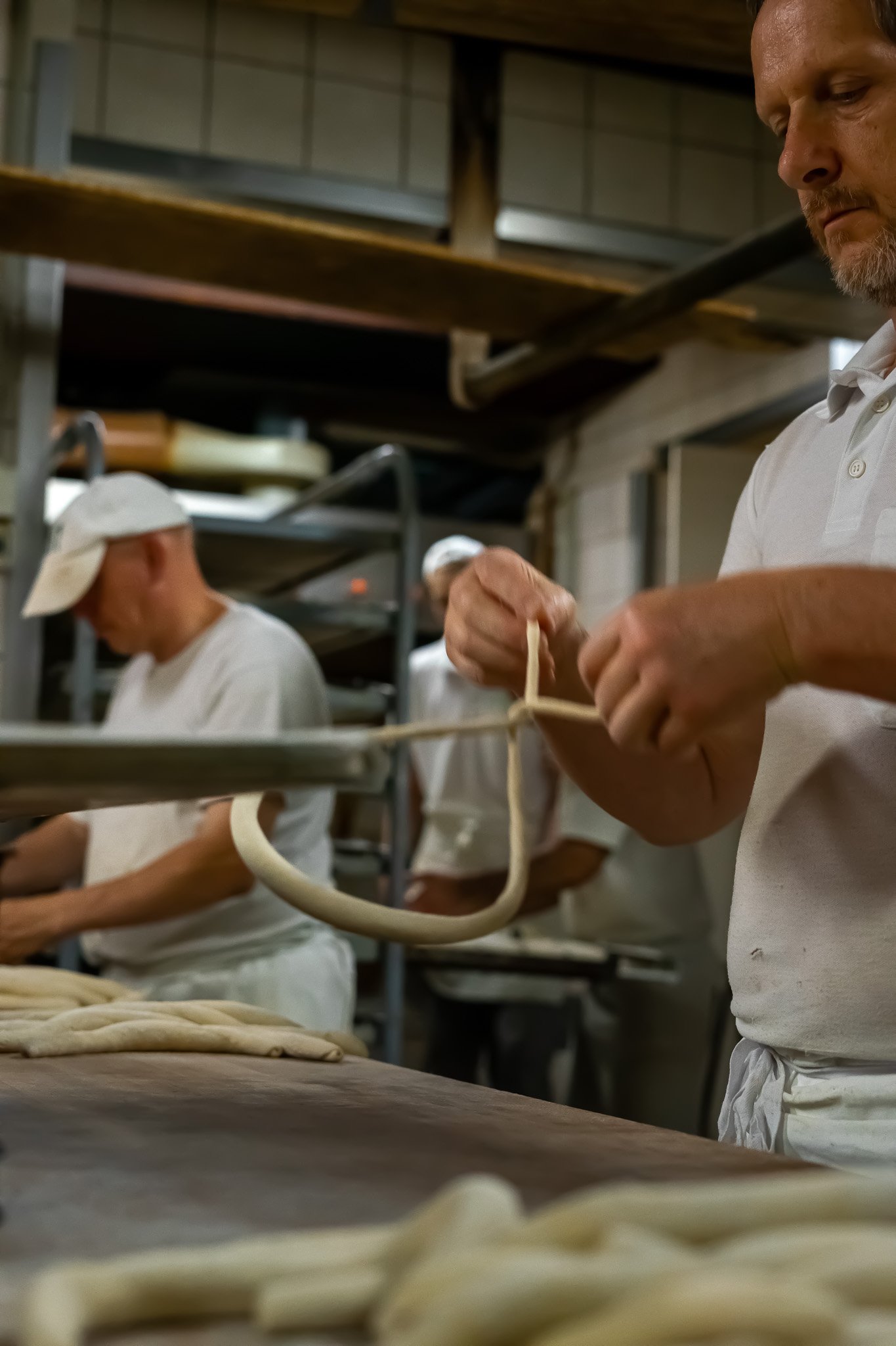 Bäcker formt Teig zu Berzeln, auch Brezn Drehen genannt, in einer Bäckerei.